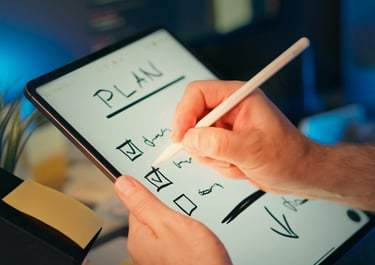 A person using a stylus pen to write a digital plan and check list on a tablet screen.