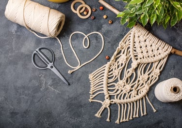 Tapiz de macramé hecho a mano con cordón de algodón, tijeras y cuentas de madera para manualidades.