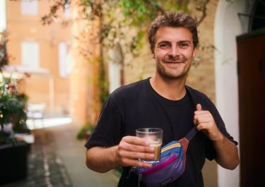 Aldan Kosnick holding a glass of coffe in a narrow alley