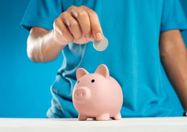 A child's hand putting a coin into a ceramic piggy bank