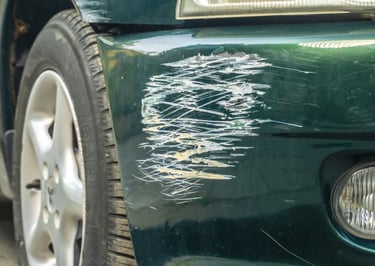 Auto verde con rayón en el parachoque causado por roce entre autos