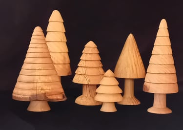 A group of golden-coloured turned wooden trees against a black background.