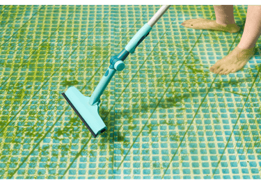 Pool tech vacuuming derbis during green to clean pool service maintenance