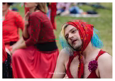 Mann mit blauen Haaren und rotem Schal übt Tanzbewegungen.