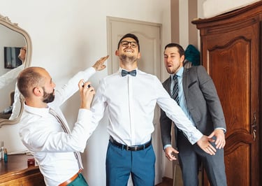Jeune marié entouré de deux amis pendant les préparatifs dans une ambiance fun et pleine de joie.