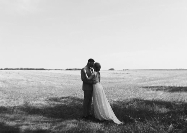 Séance couple en noir et blanc dans un champ après un mariage.