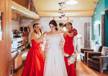 Préparatifs de la mariée entourée de ses témoins en robes rouges au Gîte du Coq à l'Âne.