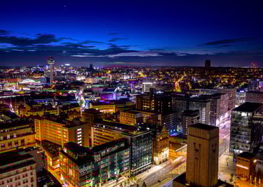 Elevated night view of the illuminated Liverpool city skyline featuring St Johns Beacon and modern urban architecture.