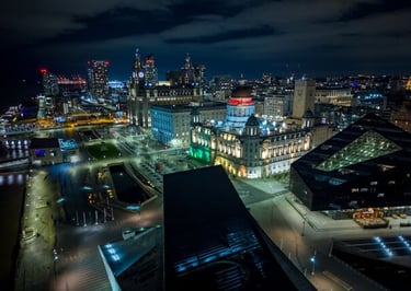 Aerial night view of Liverpool waterfront featuring the Port of Liverpool Building and city skyline.