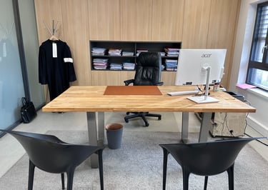 Modern lawyer office with a wooden desk, black leather chair, and a legal robe hanging in the background.