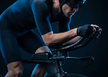 Primo piano di un triatleta PRO in posizione aerodinamica su una bici da crono, con accessori AEROTIPS ben visibili, illuminazione studio ad alto contrasto e luce di bordo blu elettrico, messa a fuoco sui dettagli tecnici.