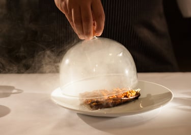 glass lid filled with smoke lifted off gormet meal