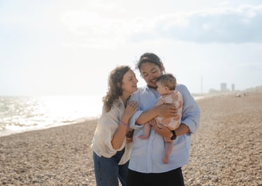 Family holding their baby on the beach during sunset