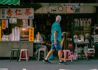 a man walking down the street in front of a Taiwanese street food vendor