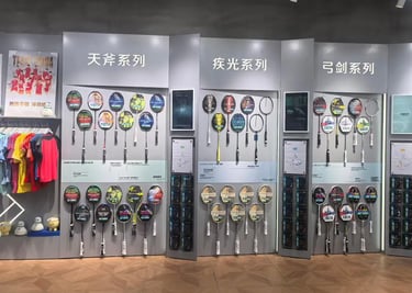Yonex badminton rackets displayed on a store wall featuring Astrox, Nanoflare, and Arcsaber series.