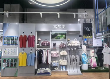 A wall display in a sports store featuring a wide variety of Yonex badminton rackets and athletic apparel.