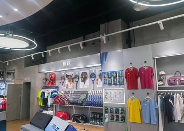 Yonex retail store interior displaying tennis racquets, sports apparel, and gear on wall racks.