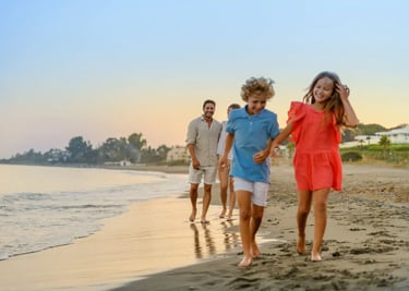 A happy family with young children walking on a sandy beach during a golden sunset vacation.