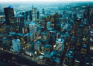 Aerial night view of illuminated Melbourne city skyline with glowing office skyscrapers and street lights.