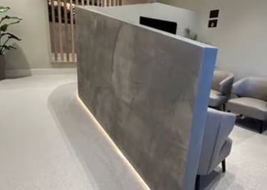 Modern dental surgery waiting room with grey chairs and a decorative microcement concrete wall with