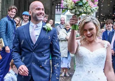 A happy bride and groom celebrate with guests as wedding confetti falls in Bury St Edmunds