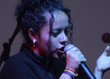 Cantante femenina de cabello rizado interpretando en vivo en el escenario con un micrófono 