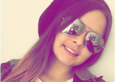 Joven sonriente con un gorro negro y gafas de sol plateadas tipo aviador, en un retrato moderno 