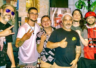Un grupo de hombres sonrientes posando junto a un controlador y una consola de DJ en un evento 