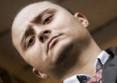 Retrato en ángulo bajo de un hombre profesional con traje gris y corbata roja estampada.