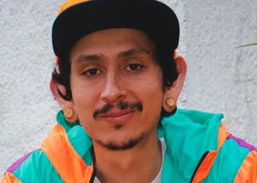 Joven con dilataciones en las orejas, usando una gorra naranja de béisbol y una chaqueta vintage 