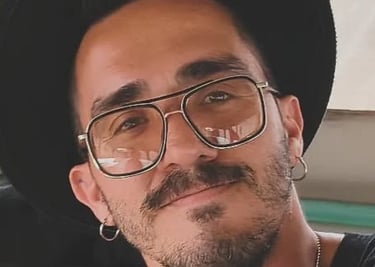 Un hombre con estilo, usando un sombrero negro de ala ancha y gafas aviador con lentes amarillos