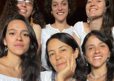 Un grupo diverso de seis mujeres sonrientes, vestidas con blusas blancas, posando juntas 