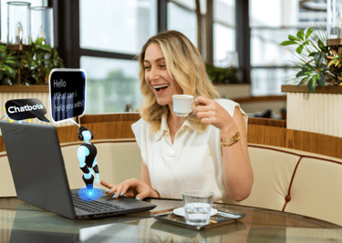 a woman sitting at a table with a laptop and a cup of coffee and chatting with a chatbot
