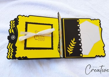 Handmade album with decorative yellow and black pages. The left page has a ribbon and text; the righ