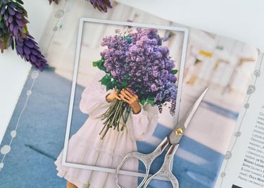 A magazine page of a person in a white dress holding a large bouquet of purple flowers.