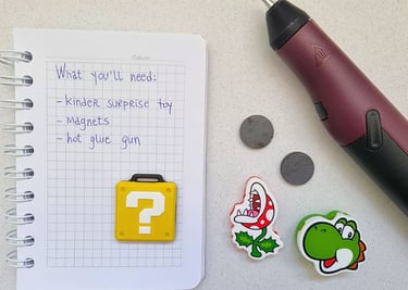 A notepad with a list of DIY materials, including a Kinder Surprise toy, magnets, and a hot glue gun