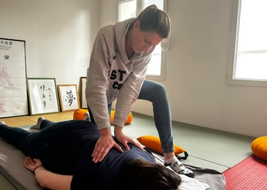 Professional practitioner performing a traditional Shiatsu massage therapy session on a floor mat.