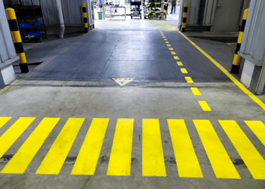 Suelo de una fabrica con paso de peatones con las líneas pintadas de amarillo.