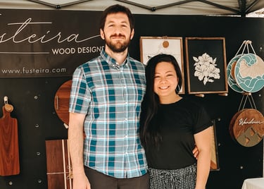 Gilliane and Victor, from Fusteira, at their booth, showcasing custom handcrafted wooden pieces.