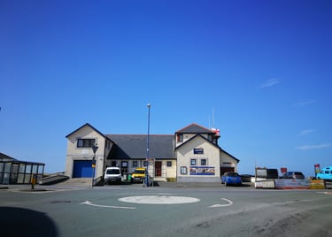 Borth RNLI Lifeboat station veiwed from the mini roundabout with blue skies
