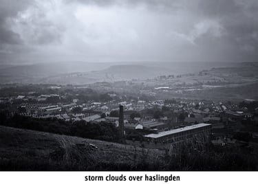 a black and white photo of storm clouds over the mill town of Haslingden