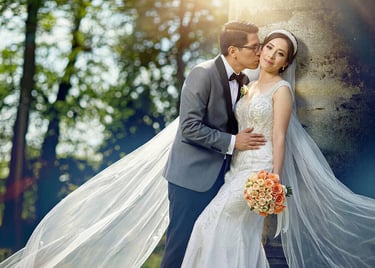 Novio besando a la novia boliviana al aire libre. Ella con vestido sirena y velo largo.