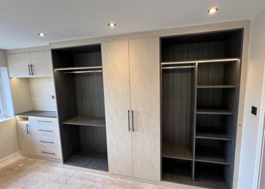 Custom built-in modern walk-in closet with integrated LED lighting, textured cream doors, and dark wood shelving.