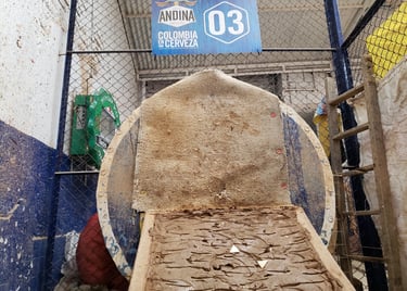 Traditional Colombian Tejo game clay court and target in a sports arena with Andina beer signage.
