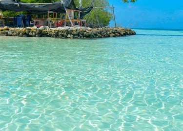 Crystal clear turquoise water ripples in front of a tropical beach bar on a sunny island.