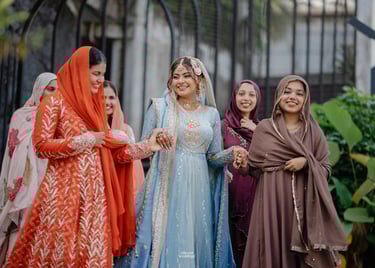 A smiling bride in a light blue embroidered Pakistani bridal dress walking with bridesmaids.