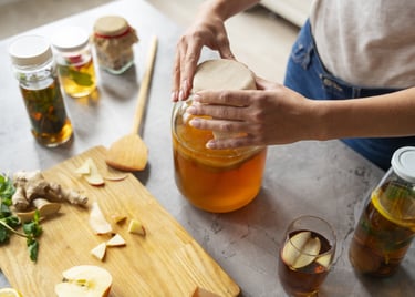 Una mujer prepara té de kombucha casero en un frasco de vidrio con un SCOBY.