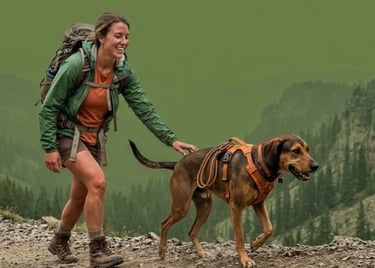 Mujer sonriente con mochila haciendo senderismo por un sendero de montaña con su perro