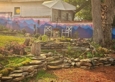 a garden with a stone wall and a patio umbrella
