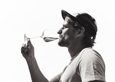 Ein Mann trinkt Wein und trägt eine Baseballmütze.